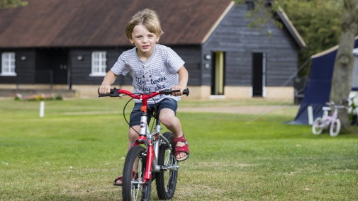 Child riding a bike on the Waterclose Meadows campsite at Houghton Mill, Cambridgeshire